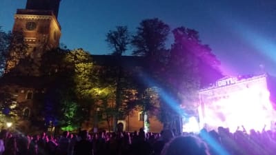 Åbo Domkyrka lyses upp i sommarmörkret av musikfestivalen Down By The Laituris lampor på huvudscenen.