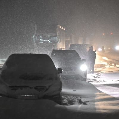 En bilkö på en fyrfilig motortrafikled i en snöstorm. Bilar ser ut att vara fast i snödrivor.
