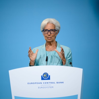 Christine Lagarde i turkos dräkt bakom ett vitt podium.