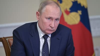 Rysslands president Vladimir Puin sitter och lyssnar vid sitt skrivbord i Kreml i Moskva.