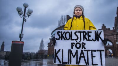 15-åriga Greta Thunberg i gul jacka, håller i en skylt med texten: skolstrejk för klimatet.