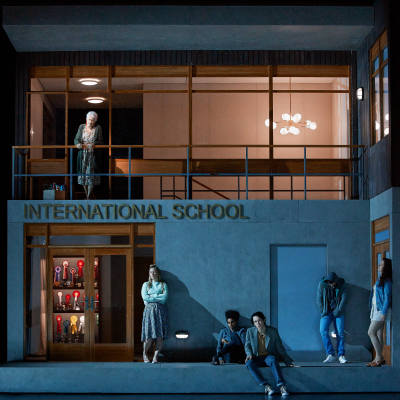 oopperalavaste, koulu, jonka seinässä lukee international school, edessä oppilaita