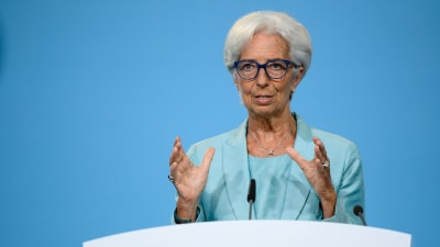 Christine Lagarde i turkos dräkt bakom ett vitt podium.