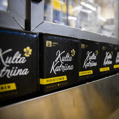 Kaffepaket av märket Kulta Katriina står i rad på ett löpande band på Meiras fabrik i Vallgård i Helsingfors.