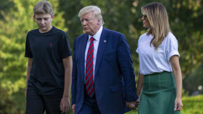 Donald Trump vandrar på en grön golfbana tillsammans med sin fru och ett av sina barn.