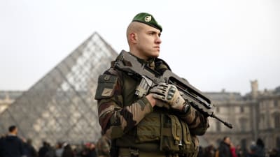 Soldat med maskingevär vaktar folkmassorna utanför konstmuseet Louvren i Paris.
