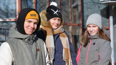 Julian Kevin, Viivi Tasanko och Elin Westerlund står ute med vinterjackor och mössor på.