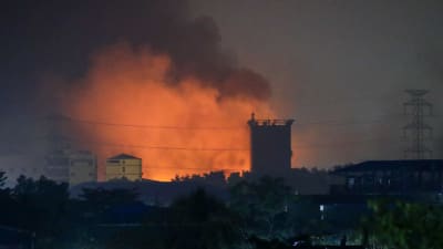 Brinnande fabriker och eldlågor slår upp mot himlen.