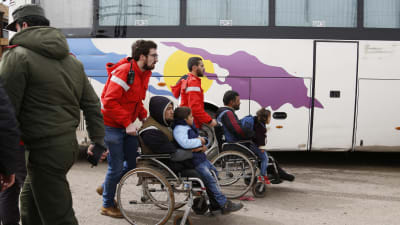 Frivilliga från den syriska Röda halvmånen hjälper skadade rebeller och deras barn att ta sig till väntande bussar