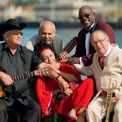 Fem musiker ur Buena Vista Social Club sitter vid kajkanten. Bland dem Eliades Ochoa och Omara Portuondo.