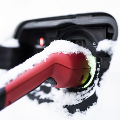 Luminen sähköauton latauspistotulppa liitettynä ajoneuvoon.