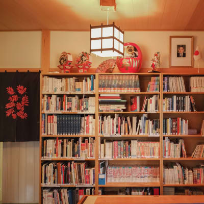 Kirjahylly, päällä Japanin ja Suomen pöytäliput, japanilainen valaisin, tekstiilejä