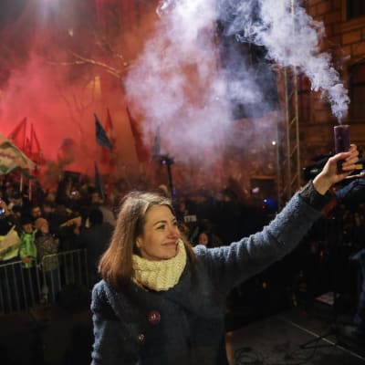 Kvinna håller i en rökgranat och i bakgrunden syns demonstranter.