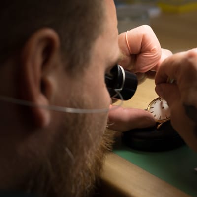 Närbild av urmakare Kari-Matti Ratsula som reparerar ett ur