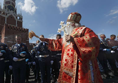 Ortodoksipappi pirskottaa vettä sotilaiden päälle.