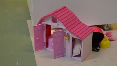 Ett rosa dockhus på ett linoleumgolv. 