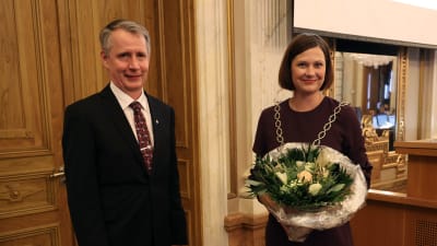 Mika Maaskola och Minna Arve står bredvid varandra i stadsfullmäktigesalen. 