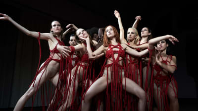 Naisten tanssiryhmä poseeraa mustaa taustaa vasten. Kuva elokuvasta Suspiria.