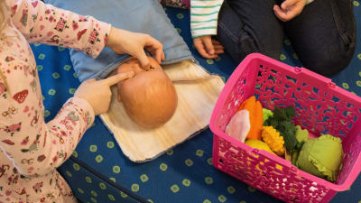Barn leker med docka på dagis