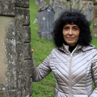 Rajaa Nadler står vid en gravsten på den judiska begravningsplatsen i Ermreuth