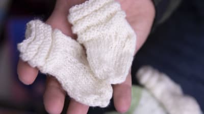 En person håller ett par babysockor i sin hand.