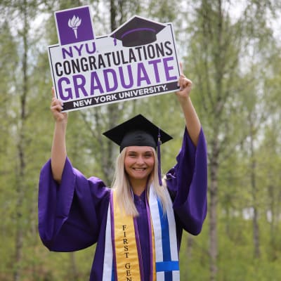 Linda Tervaniemi pitelee kylttiä, jossa lukee "NYU congratulations graduate".