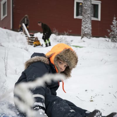 Karvahattuun ja talvivarusteisiin pukeutunut poika laskee mäkeä.