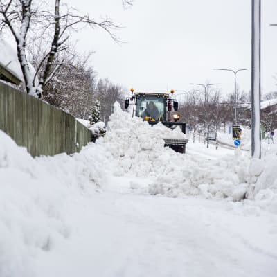 Lumiaura työntää suurta lumimäärää kadulla.