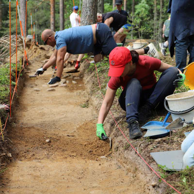 En grupp personer gräver i en grop i marken.