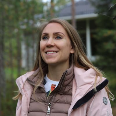 Evelina Lorek seisoo metsässä Rovaniemellä. Taustalla näkyy talo