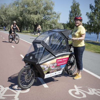 Toimittaja Tanja Perkkiö esittelee kuomullista taakkapyörää pyörätiellä.