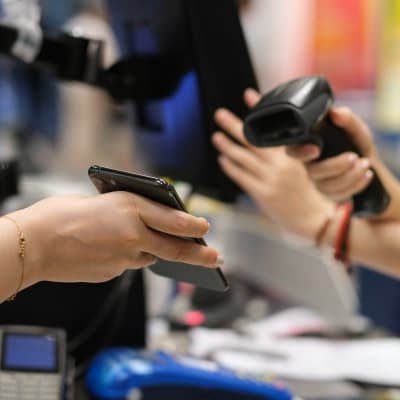 Person betalar med telefonen i en butikskassa.