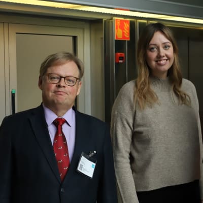 Vartiainen, Haglund och Korkman poserar framför en hissdörr. 