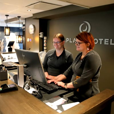 Kaksi naista hotellin vastaanottotiskillä.