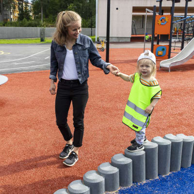 Äiti Laura Pietilä ja Toivo, 2 vuotta, kävelevät päiväkodin pihalla.