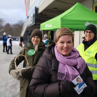 Annika Saarikko kampanjoi turkulaisen marketin edustalla vaalimainos käsissään.