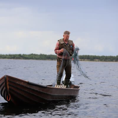 Arto Pasanen venessään heittämässä verkkoja vesille Inarijärvellä.