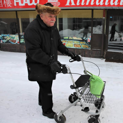 Mauri Häkälä työntää rollaattoria lumista Rautatienkatua ylös.