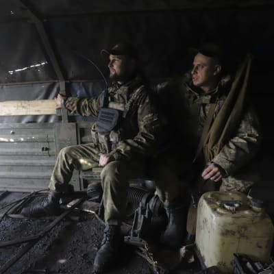 Kaksi ukrainalaista sotilasta istuu katoksen alla.