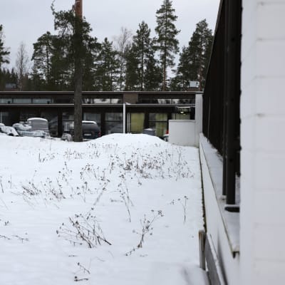 Matala rakennus lumisessa maastossa.