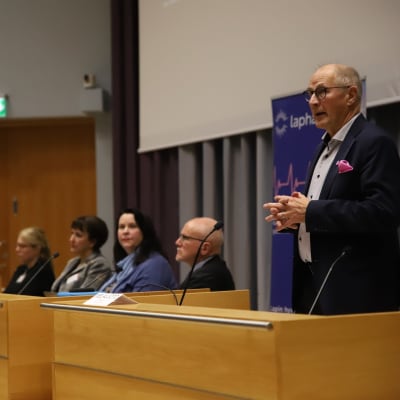 Mies puhuu puhujanpöntössä Lapin yliopiston auditoriossa.