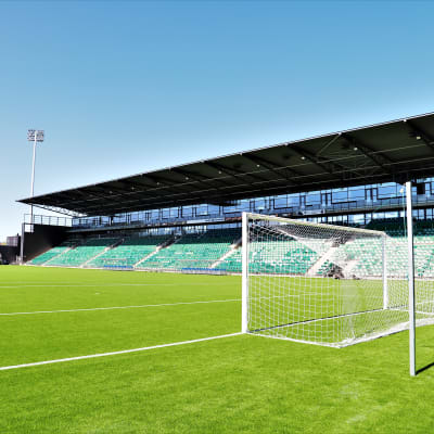 Kuppis fotbollsstadion. På bilden syns en konstgräsplan, ett mål och i bakgrunden en läktare.