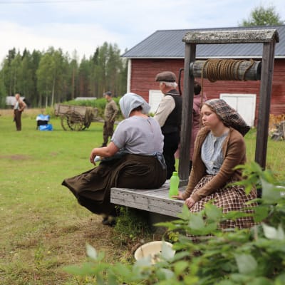 Elokuvan avustajat odottelevat kuvausten alkamista vanhan hirsitalon pihapiirissä Suvannon kylässä.