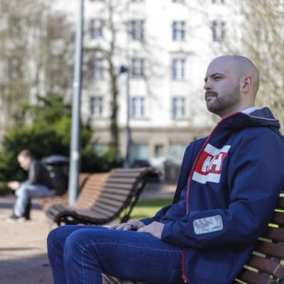 Joonas Könttä istuu puistossa penkillä.