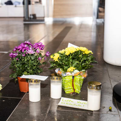 Värmeljus och blommor på golvet i köpcentret Iso Omena för att hedra minnet av en kvinna som dog där.