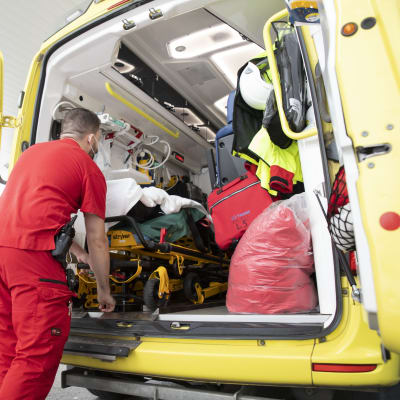 Förstavårdare lastar in en person i en ambulans.