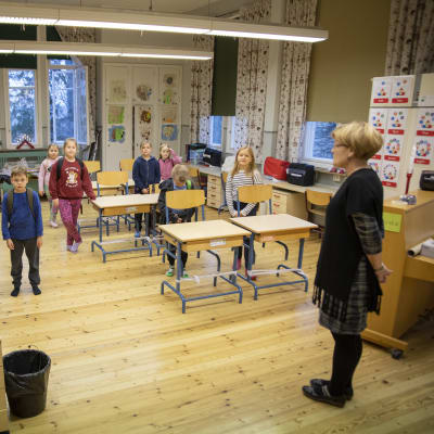 Hajalan koulun 1.-2.-luokkalaiset seisovat luokassa pulpettien vieressä Hajaln koulussa. 