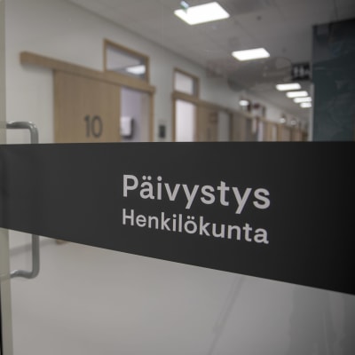 sairaalan käytävällä ovi, jossa lukee "Päivystys", ovesta näkyy läpi hoitohuoneiden ovia