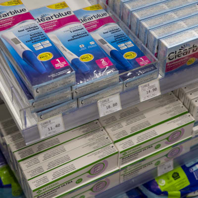 apteekin hyllyssä on kahden merkkisiä raskaustestejä.