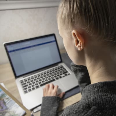 Ung person skriver studerar vid bärbar dator. 